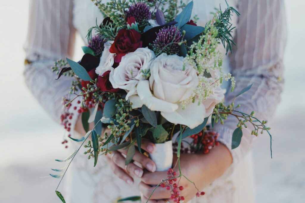 Close-up of a bride holding a beautiful bouquet at an outdoor wedding ceremony.